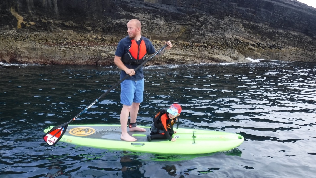 An instructor and young paddler sharing a board