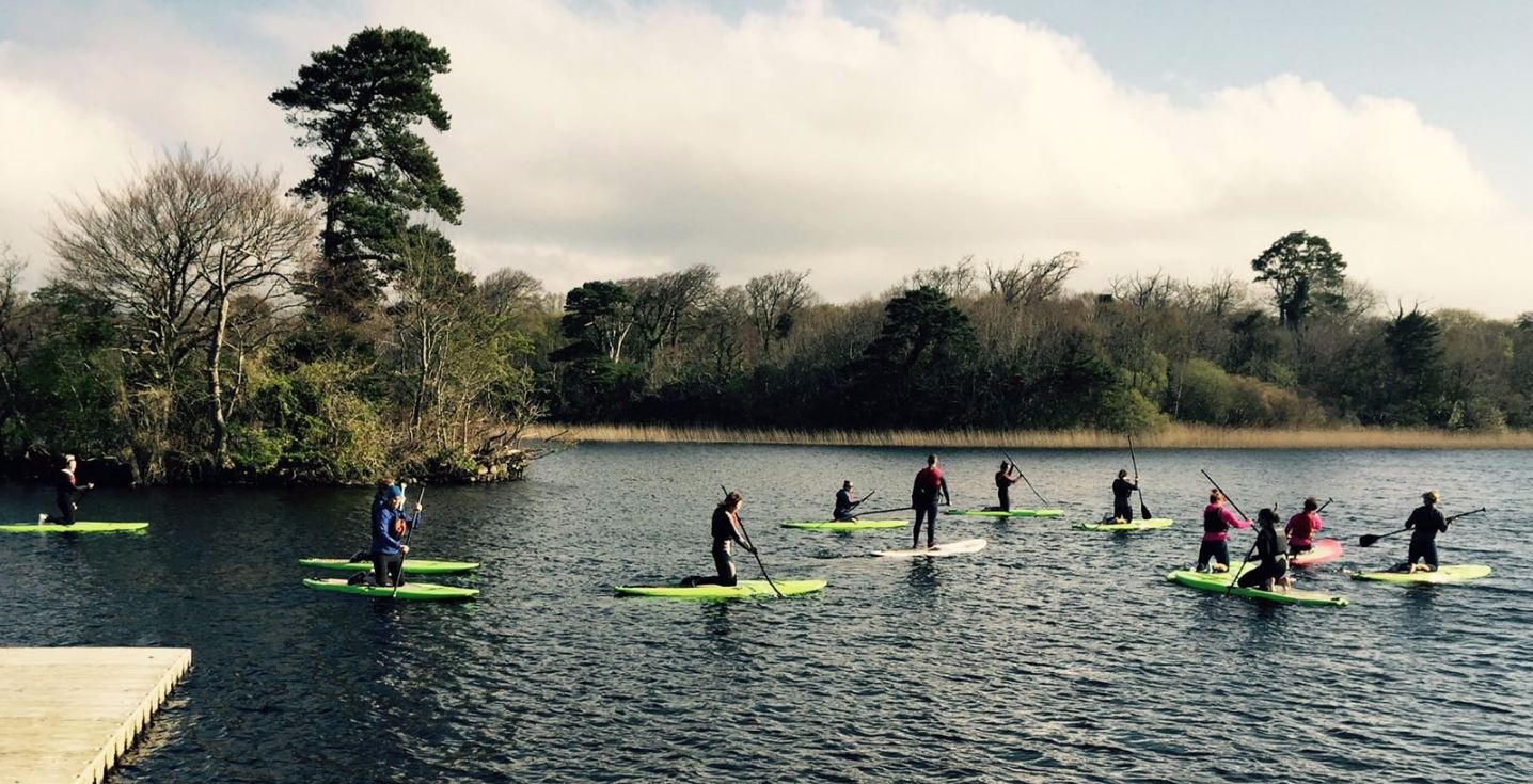 A school group with paddleboards at the lakeside