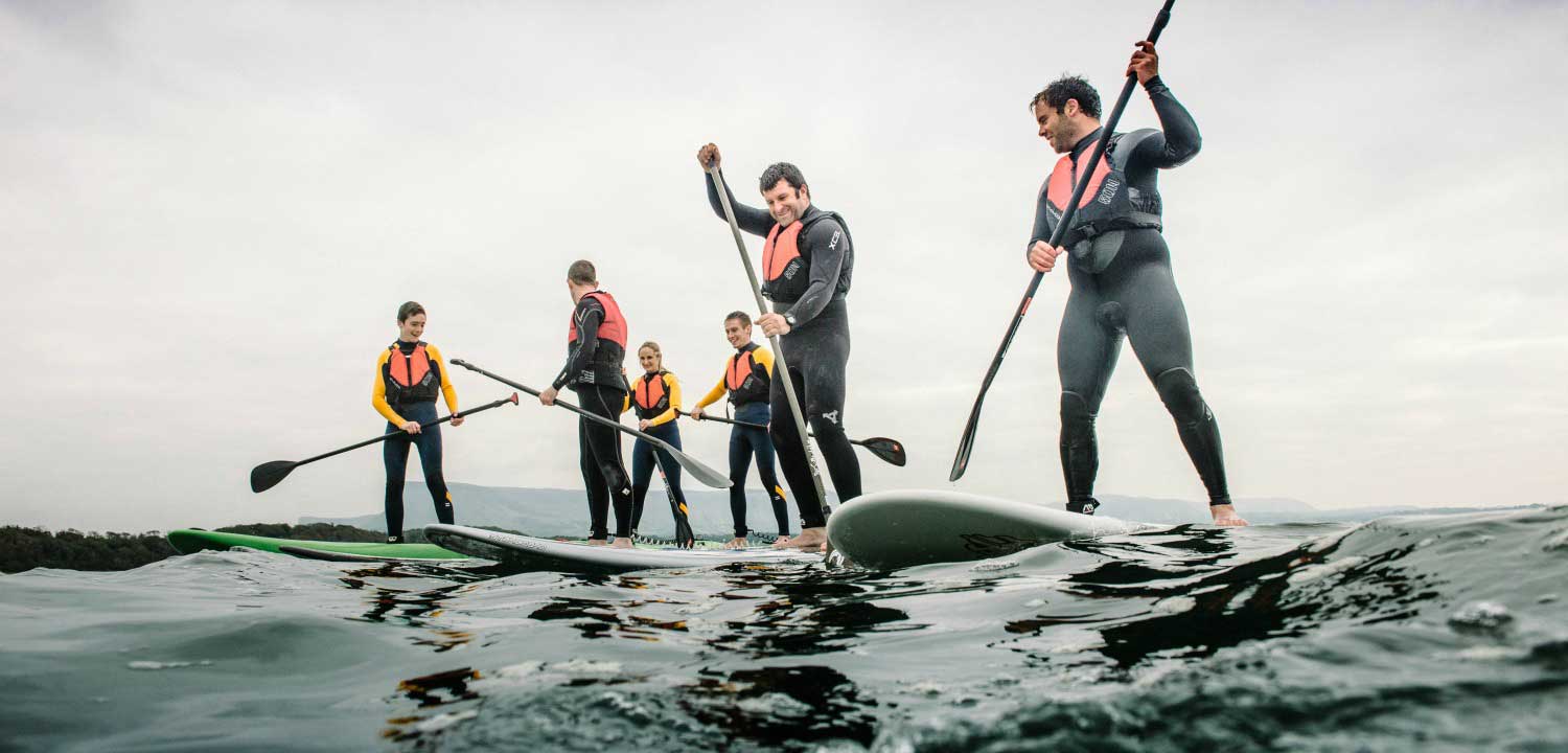 A group of adults heading out with paddleboards